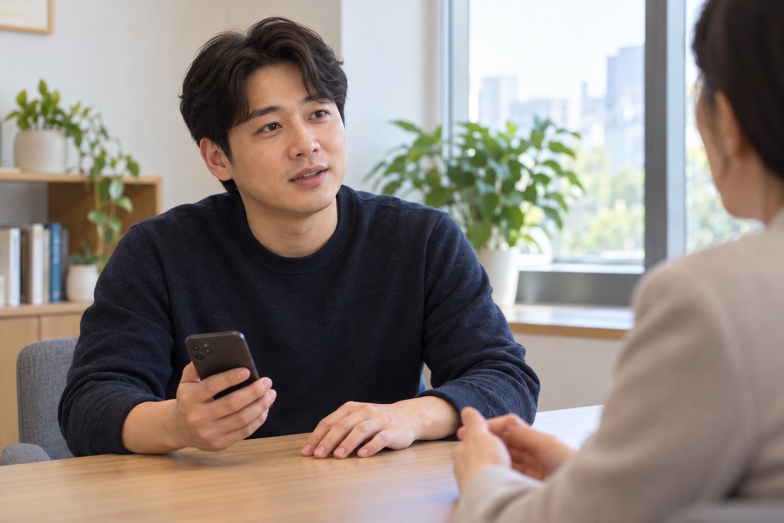 휴대전화를 손에 든 성인이 상담 자리에서 현재의 어려움을 이야기하는 모습